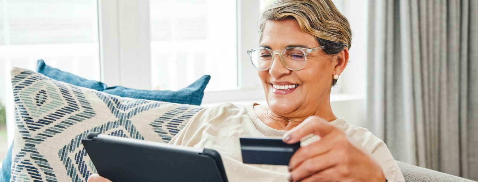 mature woman holding a credit card and a tablet