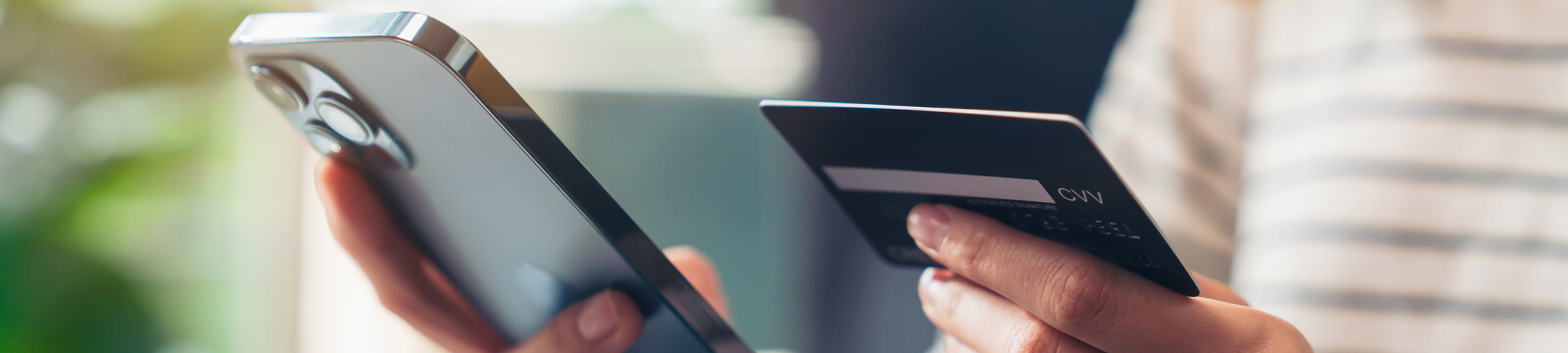 close-up of hands holding a smartphone and credit card