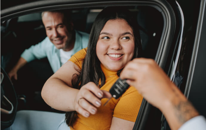 Young woman sitting in a car, taking the keys from someone out of frame