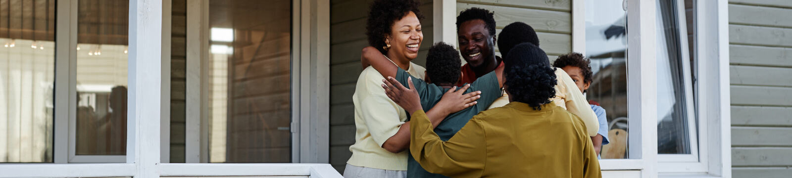 a big family hugging on the front porch of a house